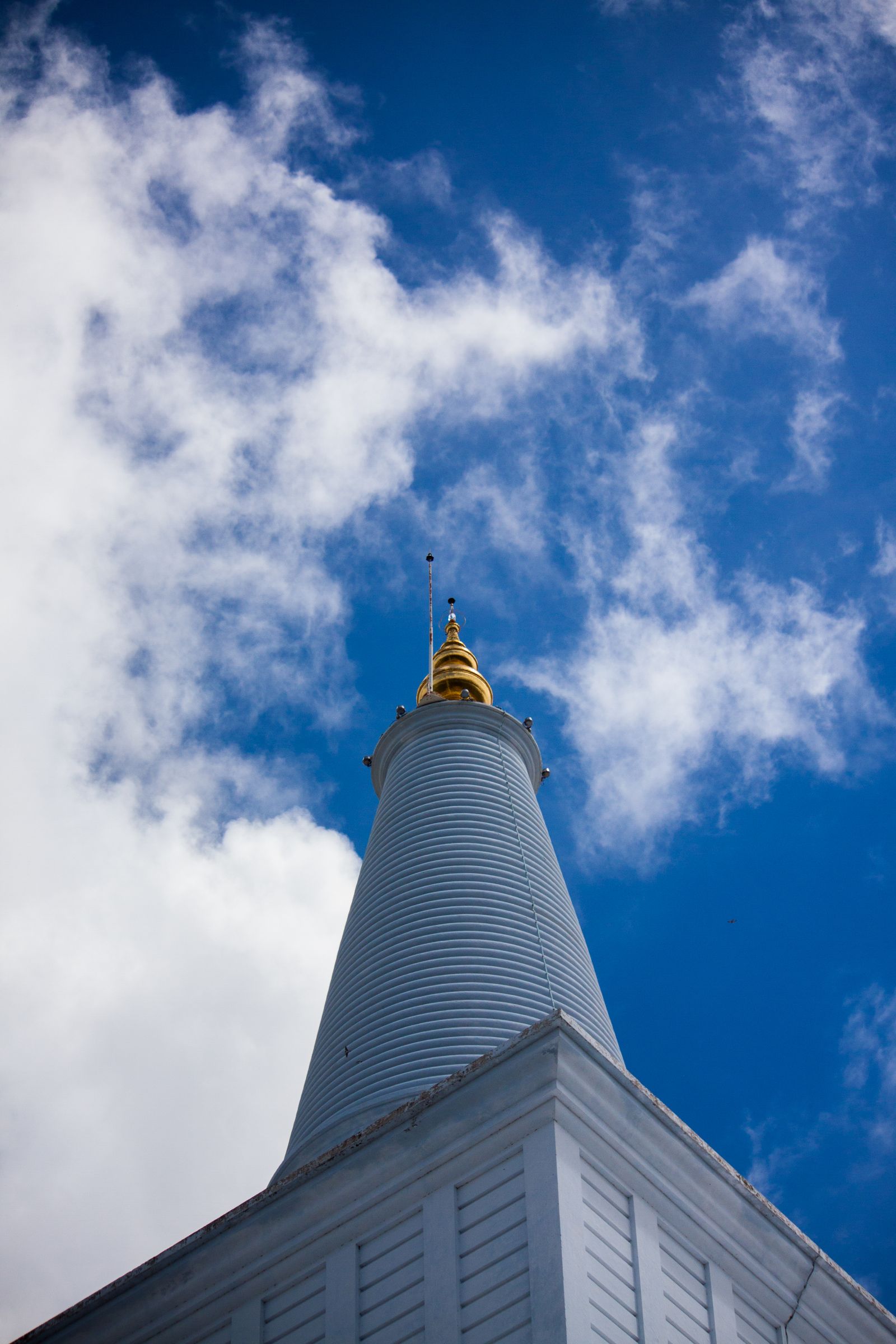 White Buddhist stupa spire against a blue sky in Sri Lanka
