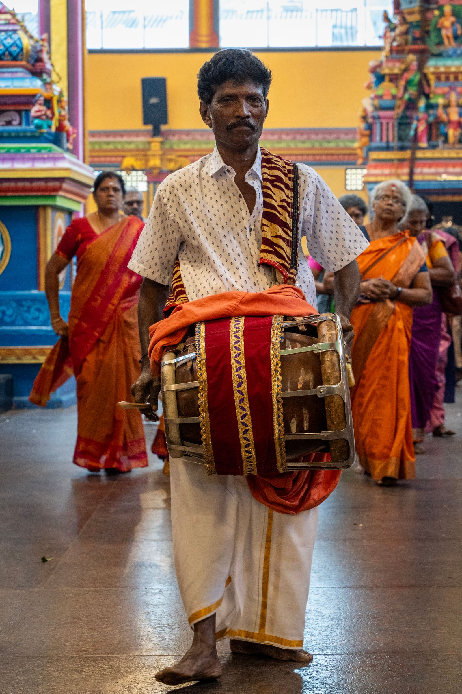 Traditional drummer leading a colorful temple procession in Sri Lanka